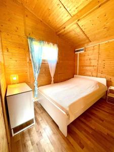 a bed in a wooden room with a window at Domki letniskowe Nadia in Grzybowo