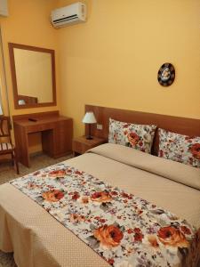 a bedroom with a bed with a flower blanket at Albergo Grande Italia in Marina di Pietrasanta