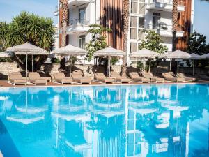 a swimming pool with chairs and umbrellas in front of a building at Rapo's Resort Hotel in Himare