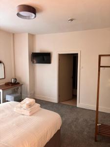 ein Hotelzimmer mit einem Bett und einem TV an der Wand in der Unterkunft Harley's in Aberystwyth