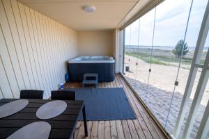 une chambre avec une terrasse avec un bain à remous et une grande fenêtre dans l'établissement Marina Resort C1, à Kalajoki