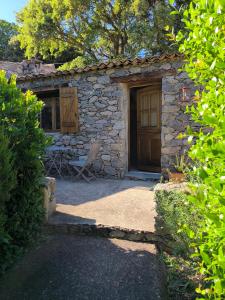 ein Steinhaus mit einer Holztür und einem Stuhl in der Unterkunft Les Bergeries de Piazzagina in Piediquarcio