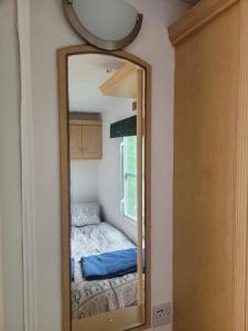a mirror in a room with a bed and a window at Postwood Gardens Country Cabins in Kentisbeare