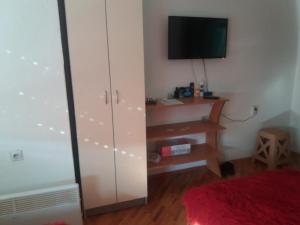 a bedroom with a white cabinet and a television at STIP Centar Private Room in Novo Selo