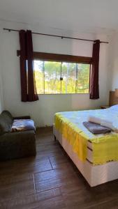 a bedroom with a bed and a window and a couch at Sítio Tabatinga in Luminárias
