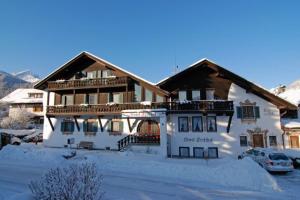 een groot gebouw met sneeuw op de grond bij Weidegg - Hotel Garni in Garmisch-Partenkirchen
