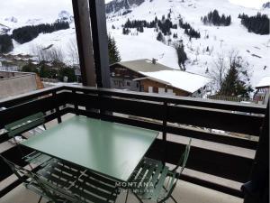 uma mesa e cadeiras numa varanda com uma montanha coberta de neve em Studio Le Grand-Bornand, 1 pièce, 4 personnes - FR-1-458-159 em Le Grand-Bornand