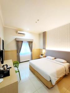 ein Hotelzimmer mit einem großen Bett und einem TV in der Unterkunft Royal Park Hotel in Samarinda