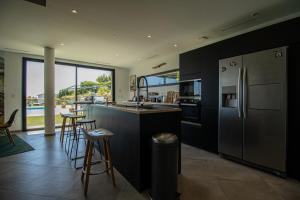 Una cocina con refrigerador y una encimera con taburetes. en Villa Carmen Écrin de Lumière en Provence, en Laouque