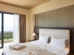 a bedroom with a large white bed with a window at Rapo's Resort Hotel in Himare