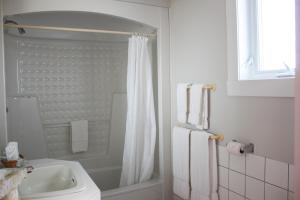 a white bathroom with a shower and a sink at Auberge le Parasol in Saguenay +37 photos