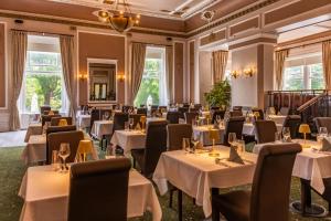un comedor con mesas, sillas y ventanas en The Palace Hotel Buxton & Spa, en Buxton