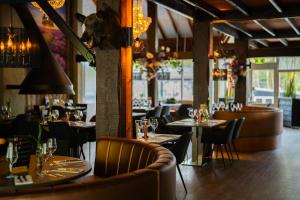 a dining room with tables and chairs and chandeliers at Vakantiepark De Rimboe & De Woeste Hoogte in Hoenderloo