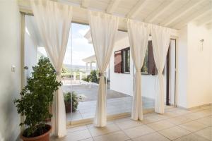um quarto com uma grande janela com cortinas brancas em Domo Bonaeras em Irgoli