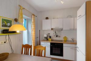a kitchen with white cabinets and a table and chairs at Möve Aba Bungalow 65 in Rerik +15 photos