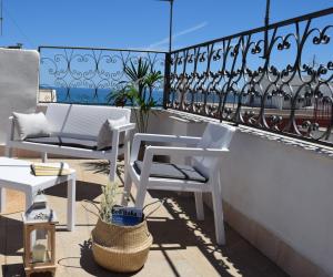Un balcón con 2 sillas blancas y una mesa. en Meridiana case al mare centro, en Mattinata