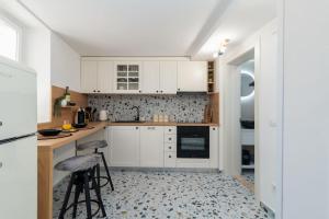 a kitchen with white cabinets and a counter and stool at Duplex apartment Domi in Slatine
