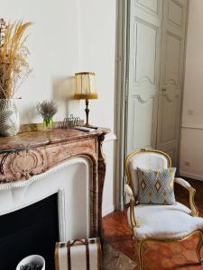 a living room with a fireplace and a chair at Les Suites du Cours & Spa in Aix-en-Provence