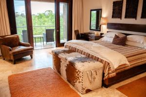 a bedroom with a bed with a ottoman and a chair at Kapama River Lodge in Kapama Private Game Reserve
