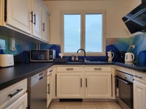 eine Küche mit weißen Schränken und einer Spüle in der Unterkunft Grand appartement 3 chambres Disney - Paris - 82m2 in Neuilly-sur-Marne