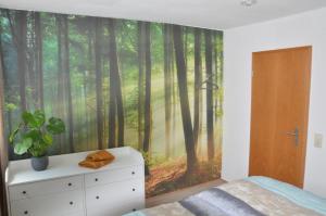 a bedroom with a wall mural of a forest at 75qm Apartment in Burgstaedt