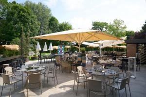 a patio with tables and chairs and umbrellas at Novotel Marne La Vallée Collégien in Collégien