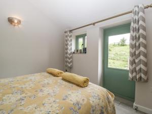a bedroom with a bed with a yellow comforter and a window at Bottom Lodge in Chepstow