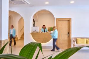 ludzie w biurze z kobietą przy recepcji w obiekcie Universal Hotel Bikini w Cala Millor +30 zdjęć