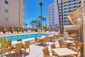 patio ze stołami i krzesłami przy basenie w obiekcie Universal Hotel Bikini w Cala Millor