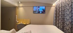 a room with a bed and a tv on the wall at Geographotel Paris-Roissy CDG Airport in Le Mesnil-Amelot