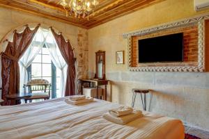 a bedroom with a large bed with a tv on the wall at Chiaro Boutique Hotel in Uchisar