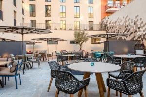 an outdoor patio with tables and chairs and a building at Motel One Barcelona-Ciutadella in Barcelona