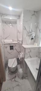 a white bathroom with a toilet and a sink at Geographotel Paris-Roissy CDG Airport in Le Mesnil-Amelot