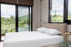 a bedroom with a white bed with large windows at Garden Inn in Himare