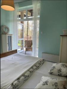 Schlafzimmer mit einem Bett und einem Fenster mit einem Stuhl in der Unterkunft Apartament Pastelowy in Krynica Morska