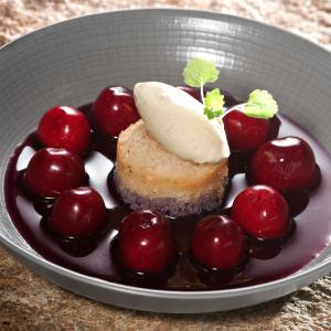 a plate of food with cherries and a piece of cake at Logis Hotel Restaurant Nougier in Saint-Étienne-de-Fursac
