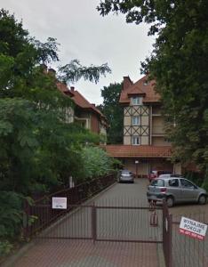 ein Zaun vor einem Haus mit parkenden Autos in der Unterkunft Apartament Pastelowy in Krynica Morska