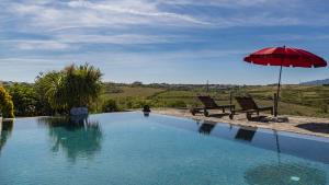 a pool with a red umbrella and a person standing in the water at Kochab Sintra by LovelyStay in Sintra
