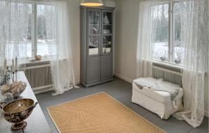a living room with a chair and a cabinet and windows at 4 Bedroom Stunning Home In Närkesberg in Närkesberg