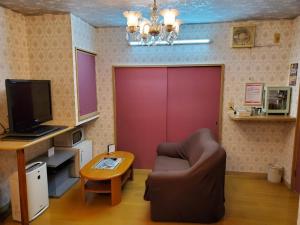 a living room with a couch and a red door at ホテル夢の里 in Miura