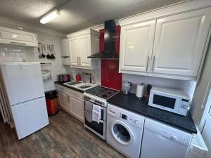 a kitchen with white cabinets and a stove top oven at Vectis Retreat in Freshwater