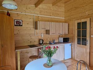 a kitchen with a table with a vase of flowers on it at Domki Radków - Skibin in Radków +28 photos