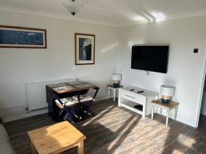 a living room with a flat screen tv and a table at Vectis Retreat in Freshwater