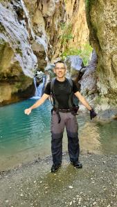 un homme debout devant une masse d'eau dans l'établissement Costas Inn, à Spílion