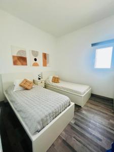 two beds in a room with white walls and wooden floors at Villa Alegría Gran Canaria Piscina Climatizada in Las Palmas de Gran Canaria
