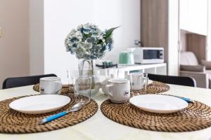a table with two plates and a vase of flowers at Felù's House in Giovinazzo