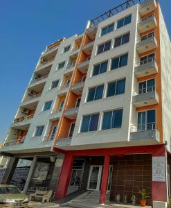 a tall apartment building with a car parked in front of it at Hotel Vista in Praia