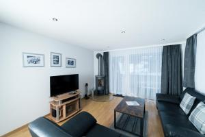 a living room with a couch and a tv at Haus Shangri-La in Saas-Fee