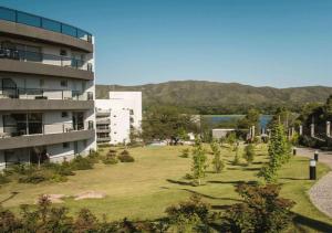 a building with a grassy yard in front of a building at Veneto Village - Vista al Lago - 10 minutos a Carlos Paz in Villa Parque Siquiman