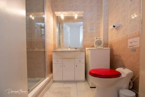 baño con ducha y aseo con asiento rojo en Pyrénées Palace en Luchon